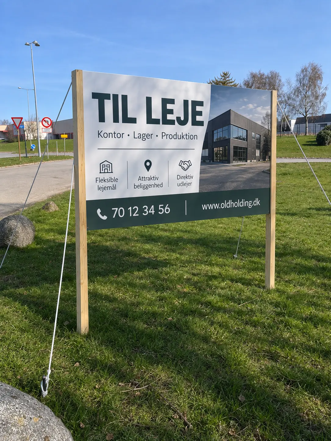 Til leje-skilt i alusandwich med bygning og kontakt, monteret på stolper