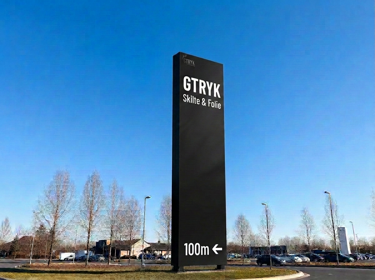 Fritstående pylon med skilteplader opsat ved en parkeringsplads